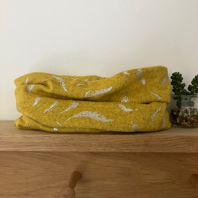 The Abella Snood Silver Feather Mustard is a wonderfully cosy and shimmering eye catching snood