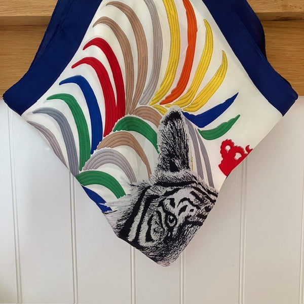 The Babar Scarf Blue is a small square that is full of colour and bold pattern