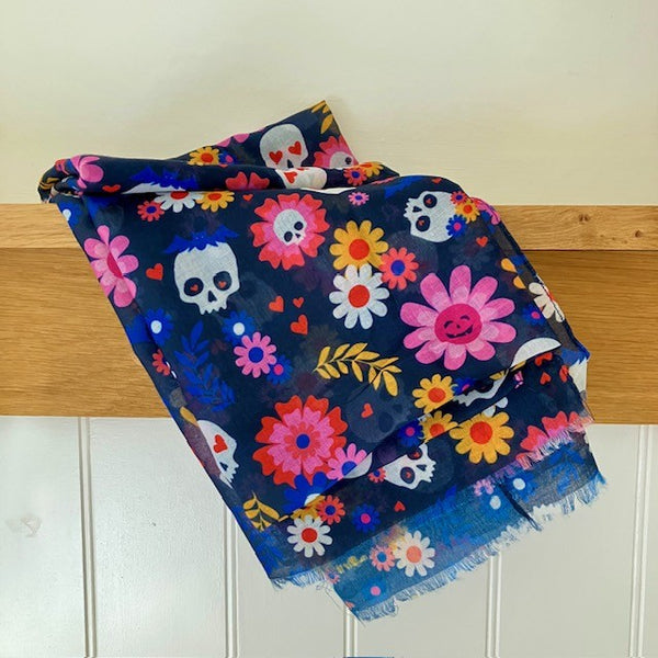 The Coco Scarf has a dark navy background with bright multicoloured pattern of spooky skulls, hearts and flowers