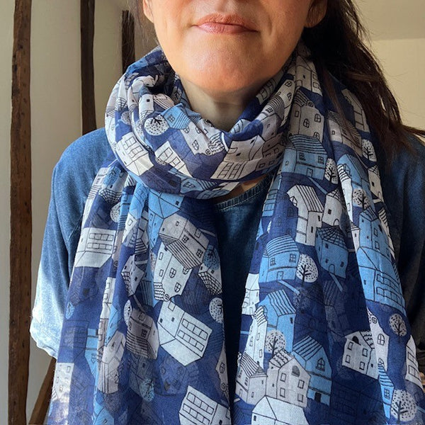 The Cosy Town scarf has a repeating pattern of little town houses, in blue, white and navy