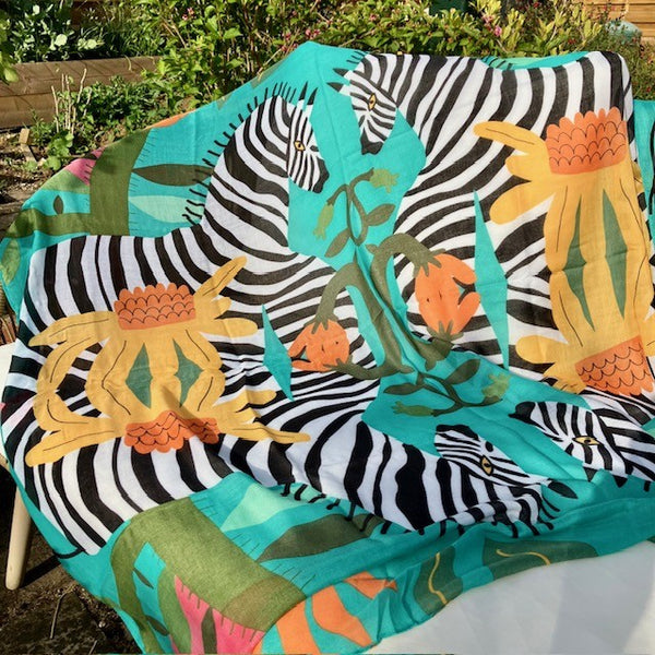 The Elio Scarf Green has a mirroring zebras and floral pattern