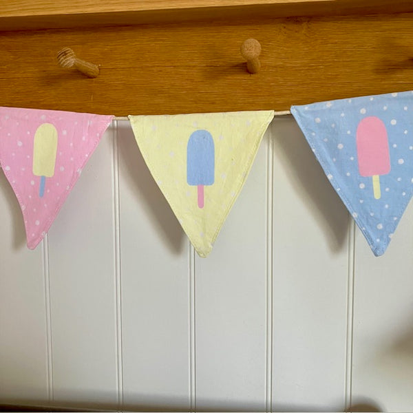 Material Bunting with ice lolly and polka dot design hanging on a wooden shelf