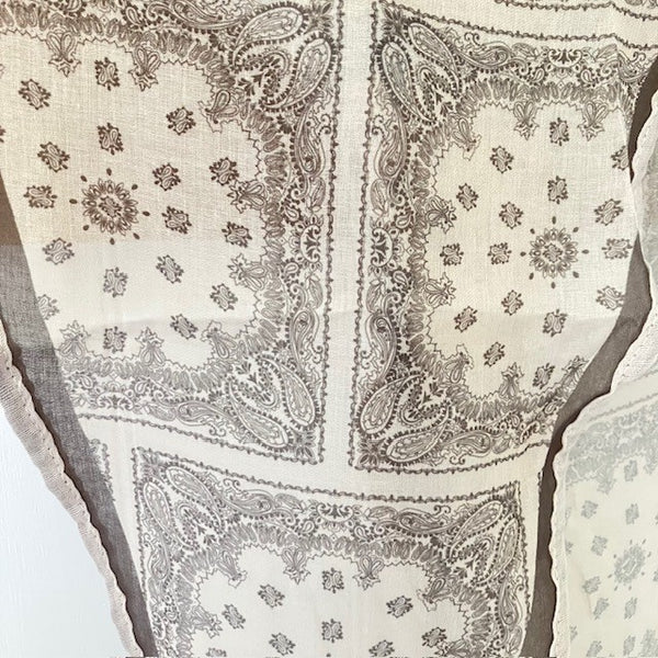 The Odette Scarf has a squares and paisley pattern in khaki on a cream background