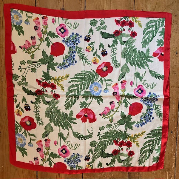 The Poppy Scarf is a square shape with a red border, creamy white background and stunning multicoloured array of cottage garden flowers