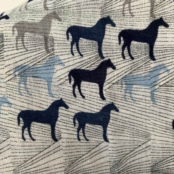The Rosaline Scarf Blue has a repeating pattern of horses an lines