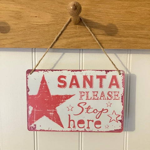 Decorative sign with 'Santa Please Stop Here' text and red stars on a rope